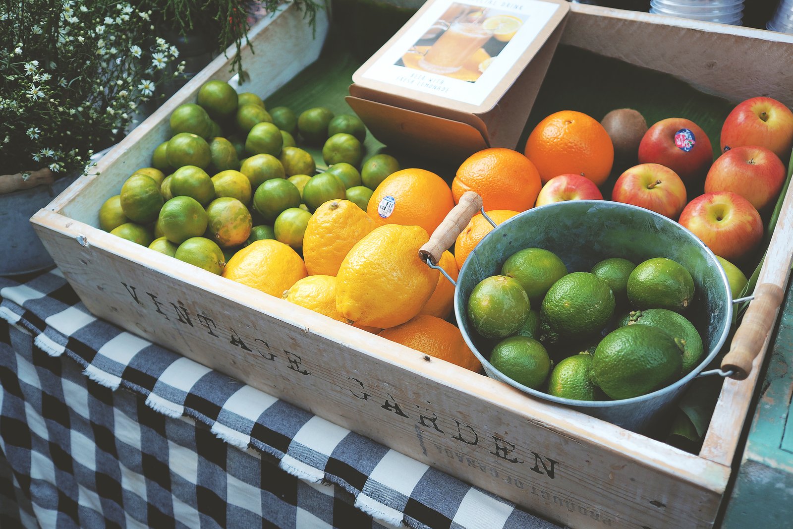 Assorted citrus and apples displayed in a wooden market crate