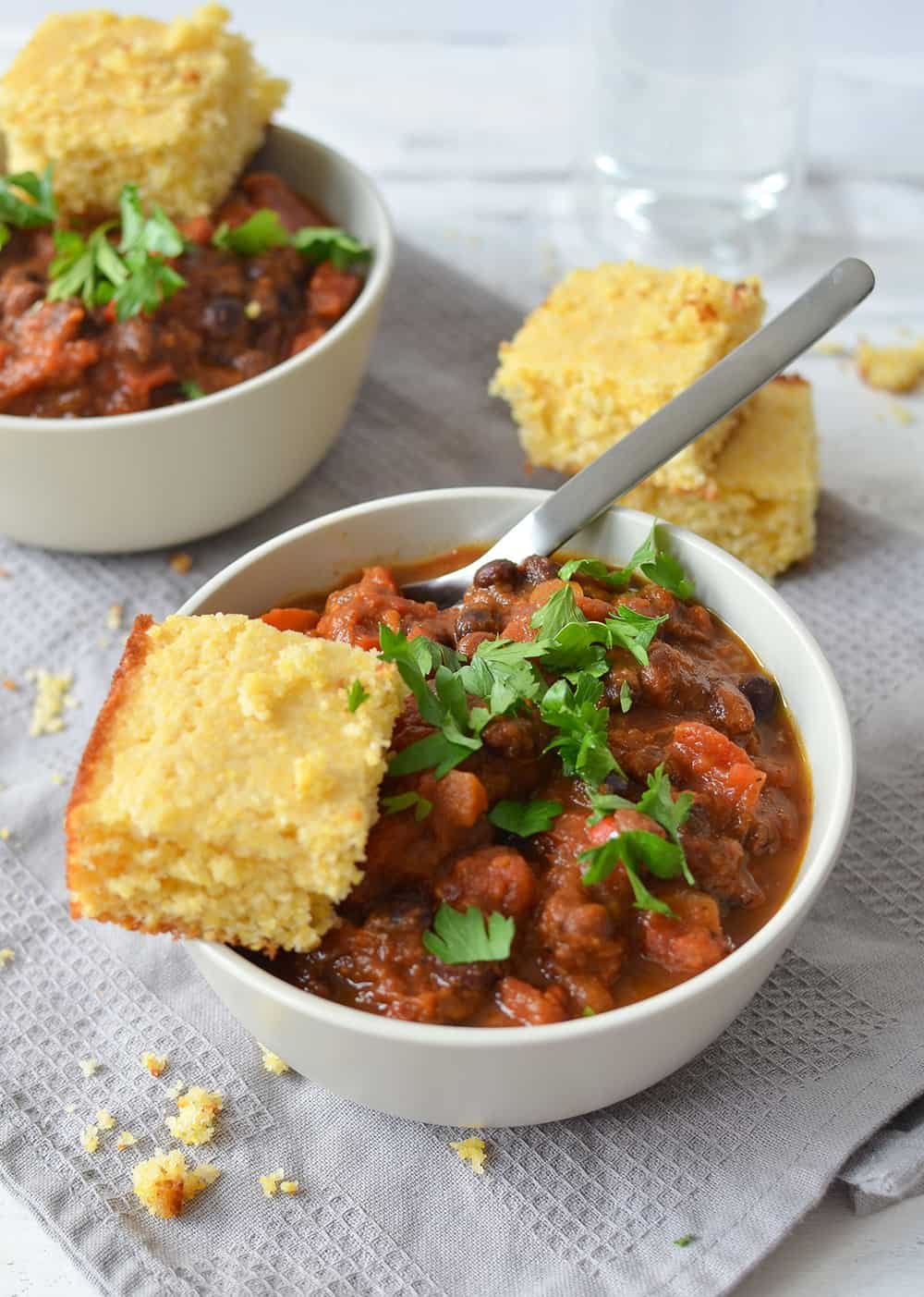 Bowls of chili topped with parsley and served with cornbread