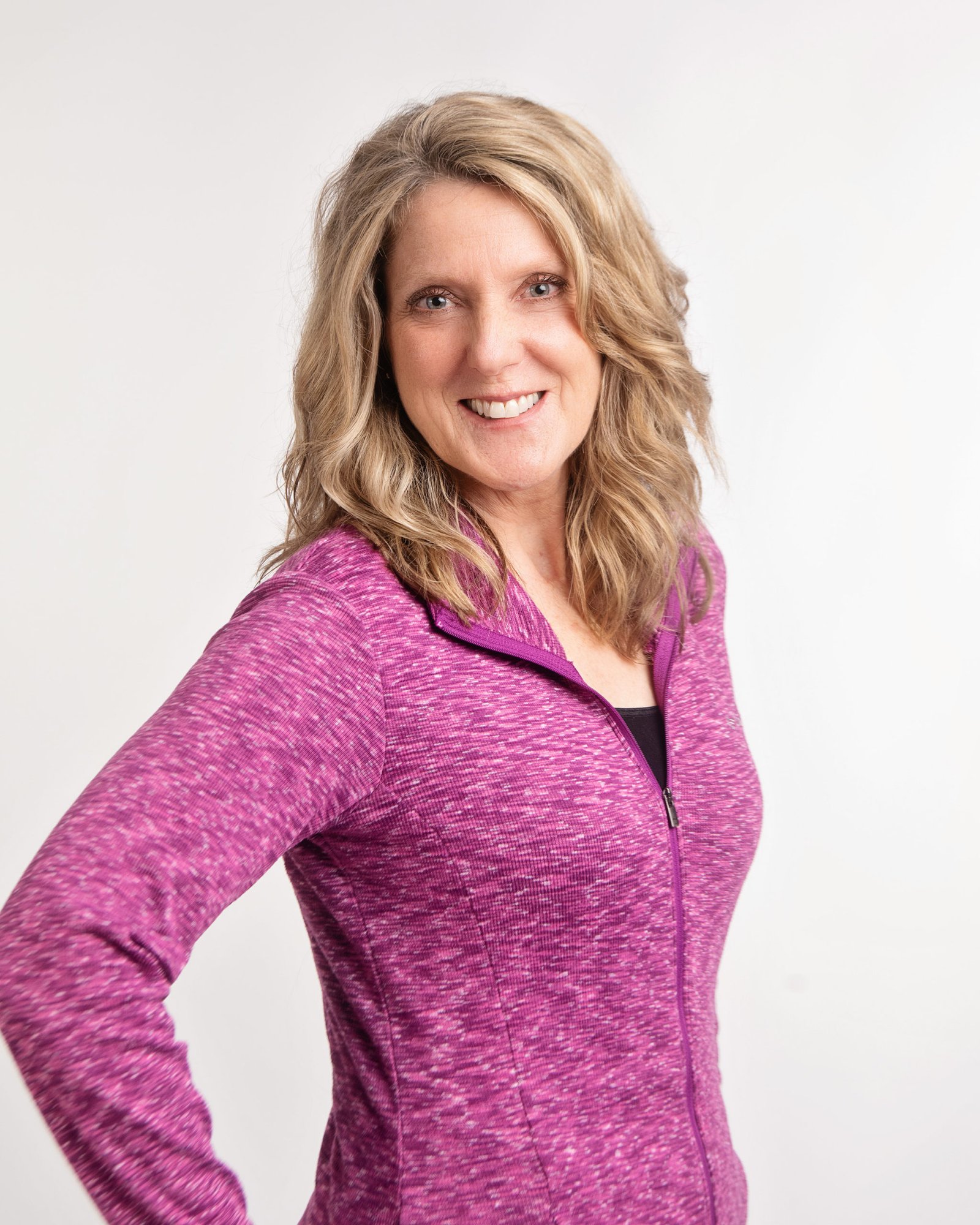 Joy Grout in a purple zip-up jacket against a white background