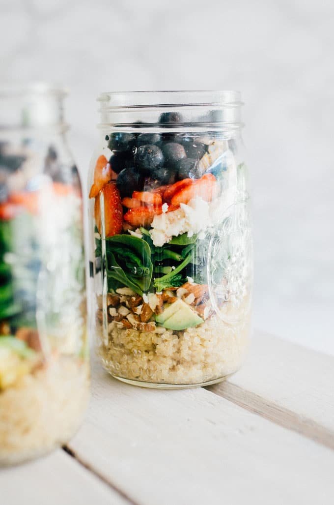 Mason jar salad with quinoa, spinach, avocado, strawberries, and blueberries