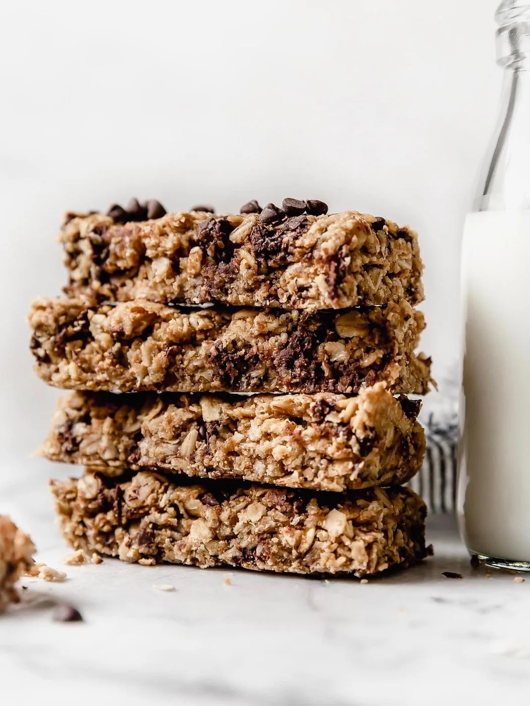Stack of oatmeal chocolate chip bars beside a glass of milk