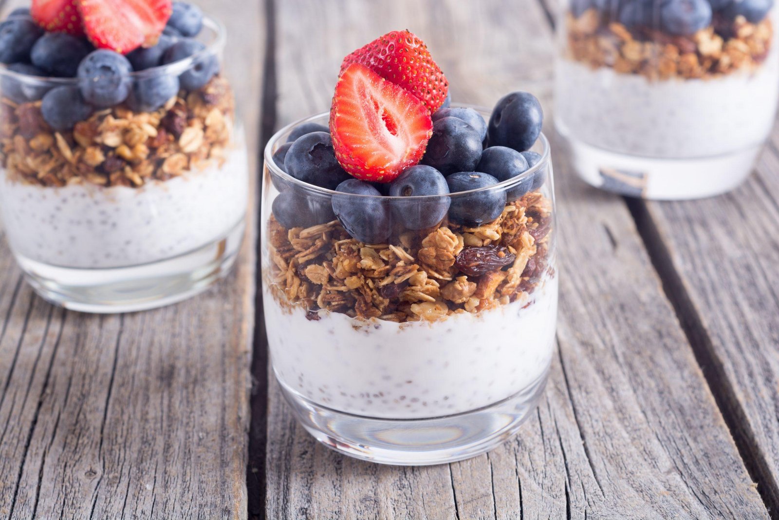 Yogurt parfait topped with granola, blueberries, and sliced strawberries