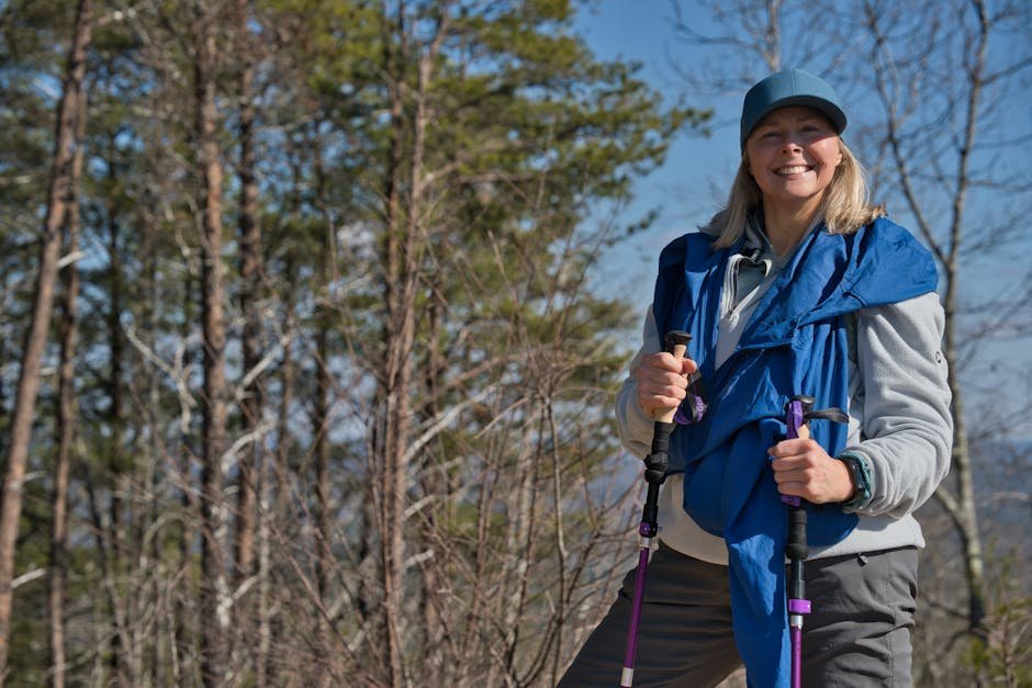 Smiling woman hiking with trekking poles in a wooded area