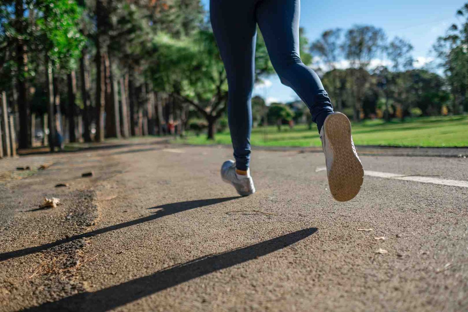 Person running on a park path, seen from behind at ground level