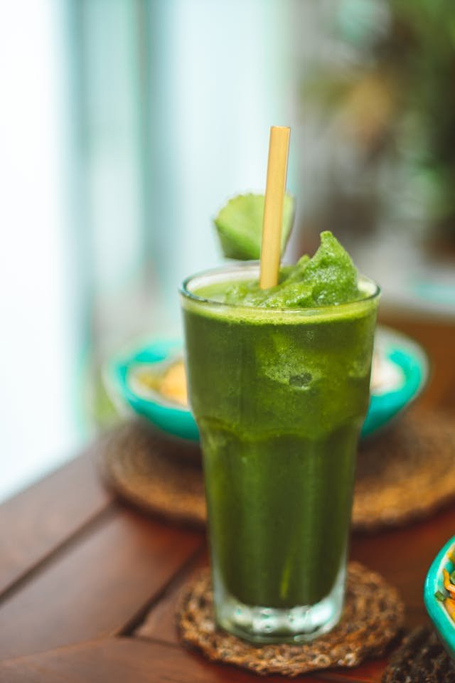 Green smoothie in a tall glass with a straw